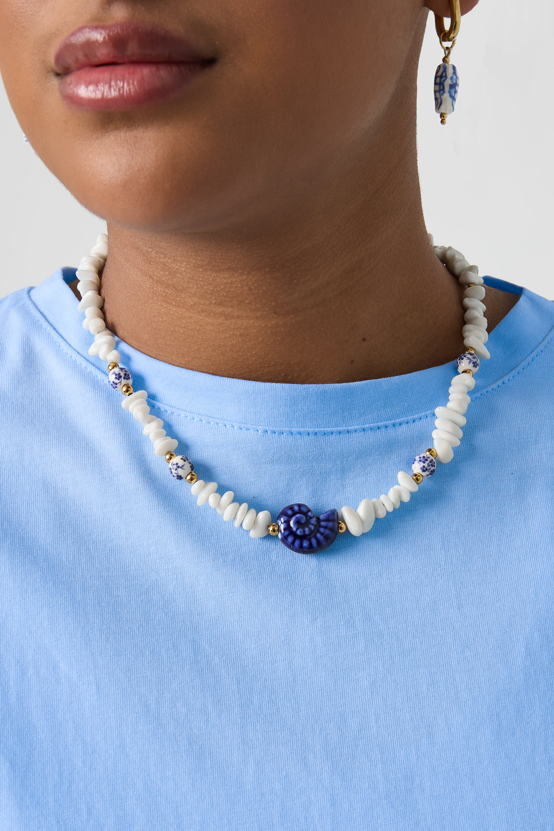 Collana con perline di pietra, perline bianche con fiori blu e conchiglia vistosa
