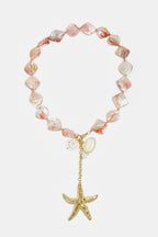Collana con perline di conchiglia, ciondoli e una stella marina pendente.